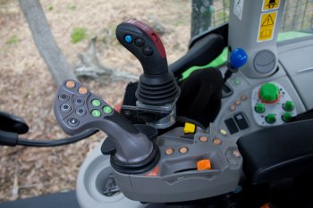 Šedý joystick slouží k ovládání funkcí traktoru včetně pojezdové rychlosti a černý joystick k ovládání rampovacího nakladače