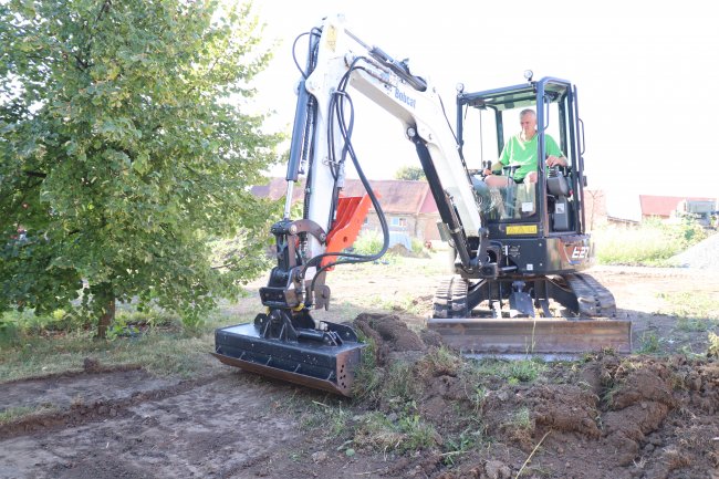 Bobcat E27 při odhrnování zeminy.